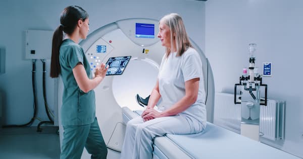 A patient sitting on a table prepares for an MRI for brain scans.
